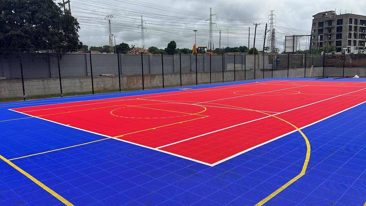 Completed black mesh perimeter fence beside a Ghana sports court