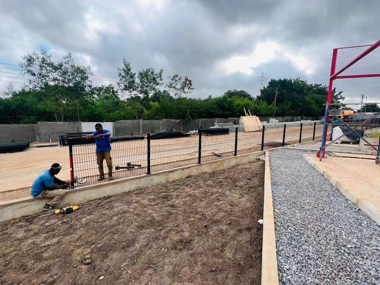 Workers installing modular welded mesh fence panels in Ghana