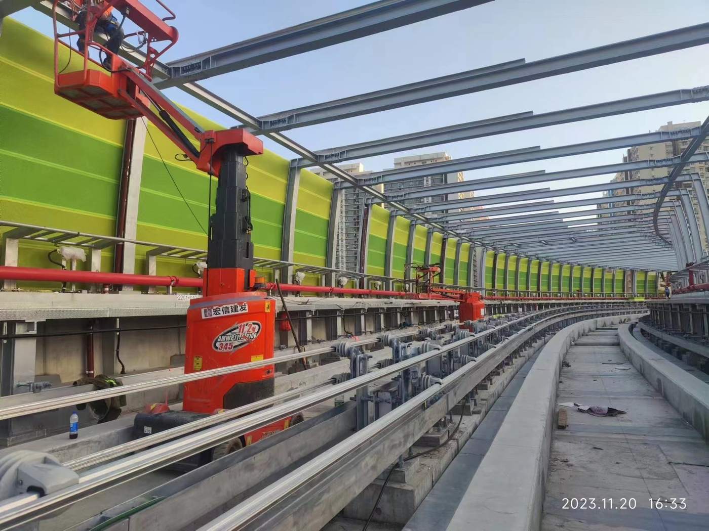 Crew using a boom lift to install noise barrier panels along an elevated line